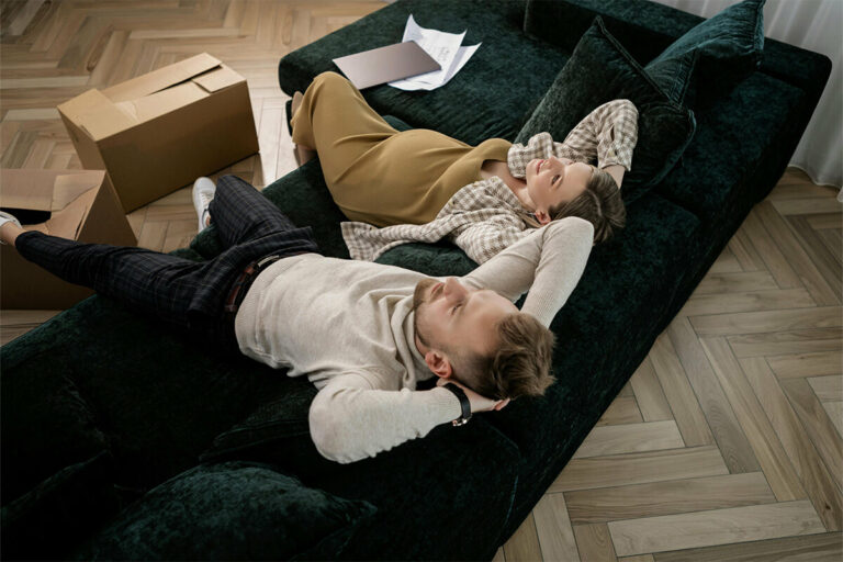 Couple sitting on a sofa surrounded by boxes